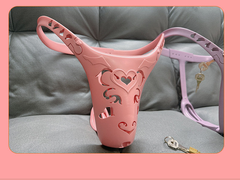 Pink heart-cutout chastity belt photographed with a purple belt and keys